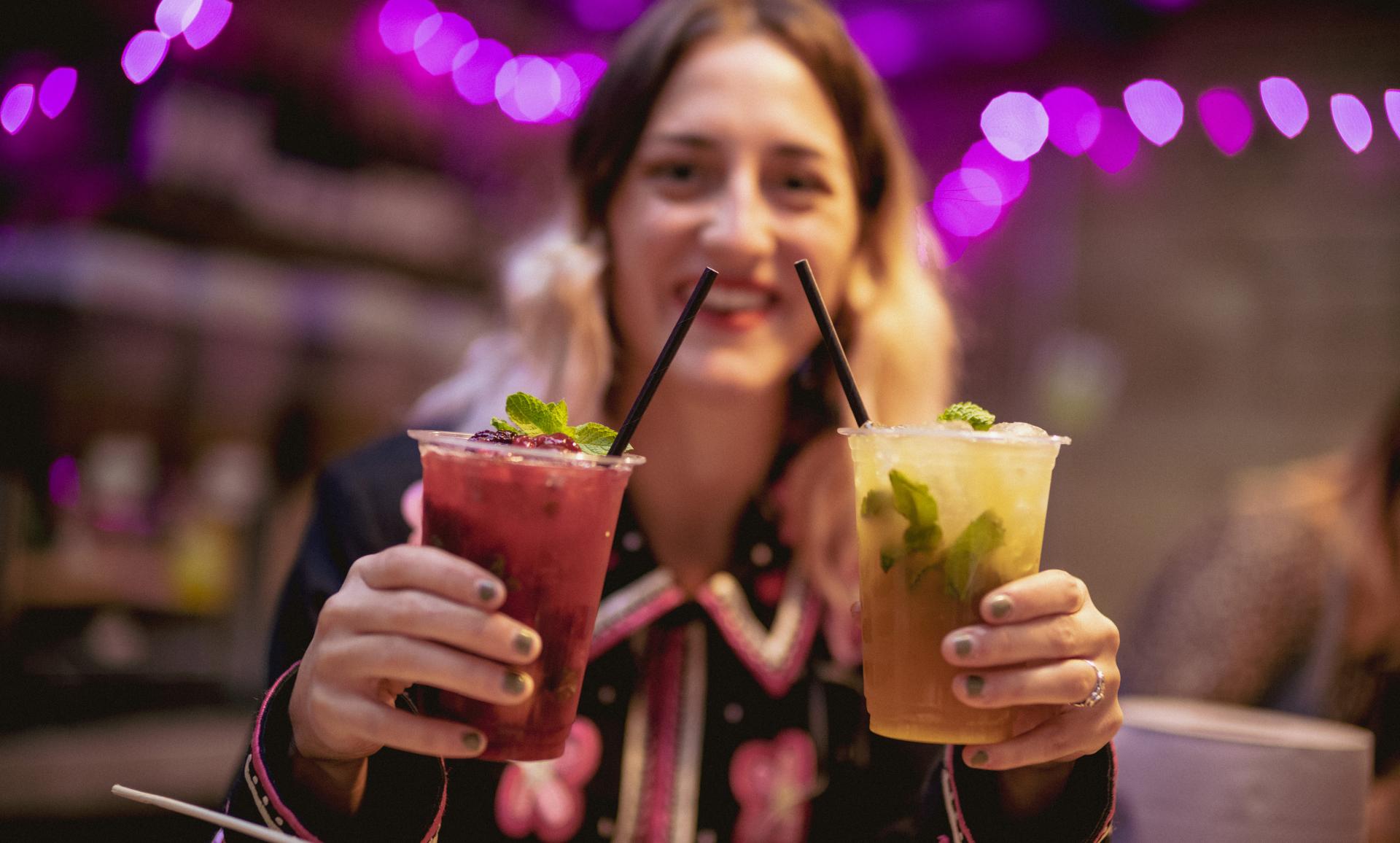 a girl holding 2 drinks